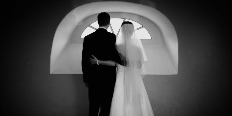 Image: Bride and groom looking out a window.