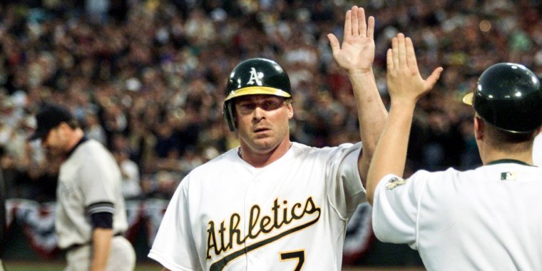 Oakland Athletics Jeremy Giambi, center, is congratulated after scoring in the fifth inning as New York Yankees pitcher Roger Clemens walks back to the mound during the first game of the American League 2000 Division Series in Oakland, Calif., on Oct. 3, 2000.