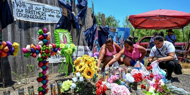 Unas mujeres colocan flores y velas en un monumento improvisado donde se descubrió un remolque con migrantes dentro, en las afueras de San Antonio, Texas, el 29 de junio de 2022.