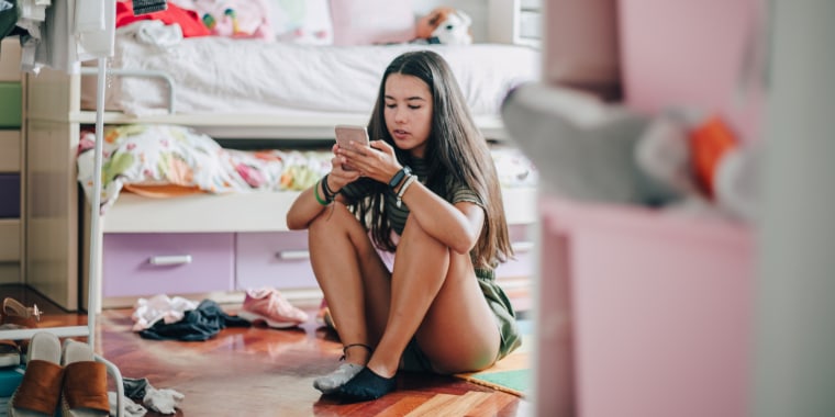 Una adolescente utiliza un dispositivo móvil en casa.