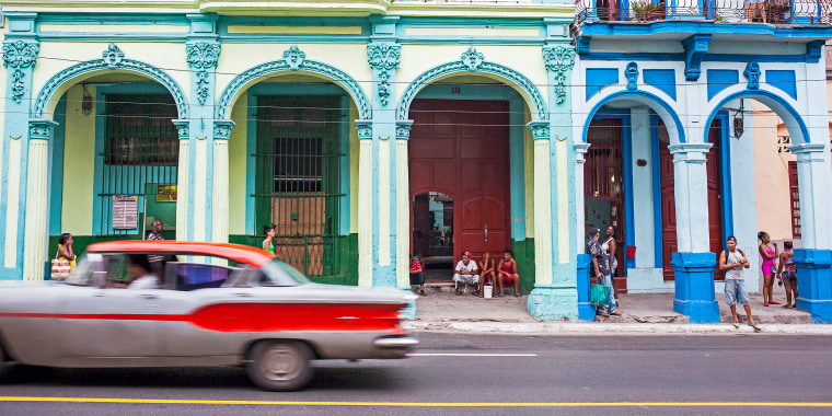 A car moves past residents in Centro Habana, La Habana, Cuba, on Oct. 23, 2015.