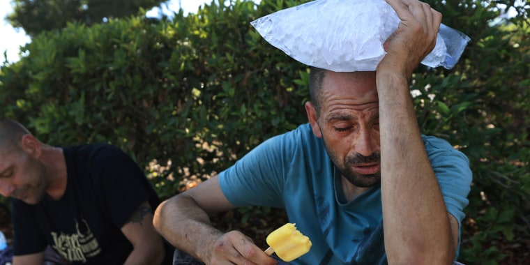 A man cools off with a popsicle and a bag of ice as the temperature in Santa Rosa, Calif., pushes 112 degrees, on Sept. 5, 2022.