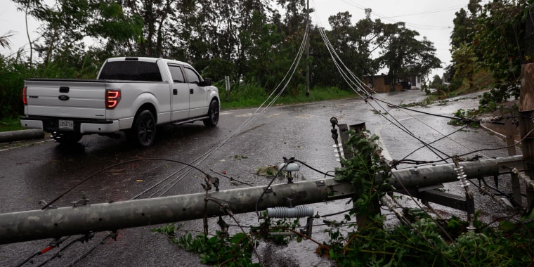Hurricane Fiona hits Puerto Rico, knocking out power across the island. Downed power line stretching across a road, with a truck parked next to it.