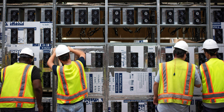 Workers install a new row of Bitcoin mining machines
