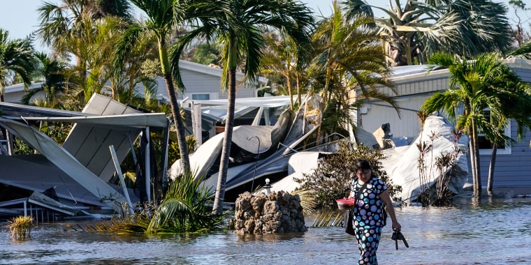 Image: Holly Nugyn walks out of her flooded neighborhood after Hurricane Ian passed by the area on Sept. 29, 2022, in Fort Myers, Fla.