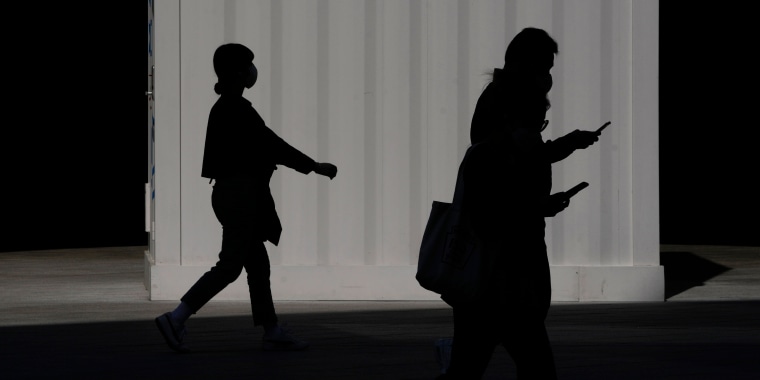Pedestrians are silhouetted as they walk in Seoul, South Korea, on May 4, 2022. 