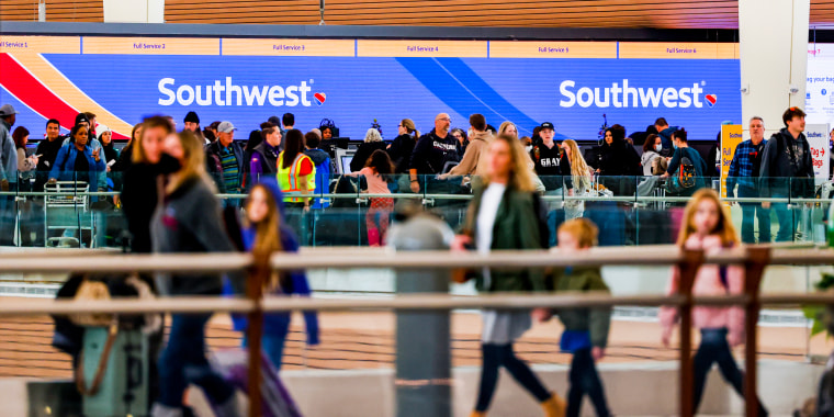 Travelers walk past the Southwest Airlines check-in counter at Denver International Airport on Dec. 28, 2022.