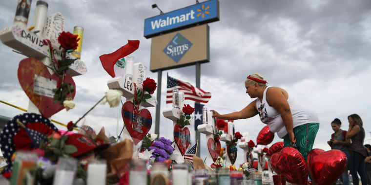A woman touches a cross at a makeshift memorial for victims outside Walmart, near the scene of a mass shooting which left at least 22 people dead, on August 6, 2019 in El Paso, Texas. A 21-year-old white male suspect remains in custody in El Paso, which sits along the U.S.-Mexico border. President Donald Trump plans to visit the city August 7.