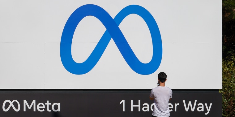 A person takes photos of the"Meta" sign in Menlo Park, Calif.