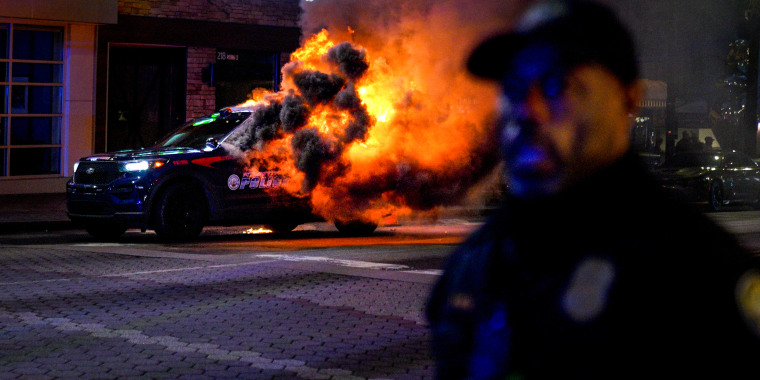 Firefighters work to extinguish a fire after an Atlanta police vehicle was set on fire during a "Stop cop city" protest in Atlanta on Jan. 21, 2023.