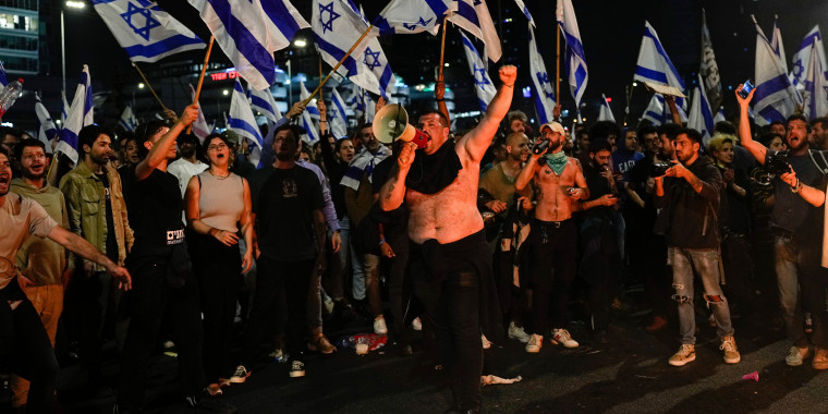 Israelis opposed to Prime Minister Benjamin Netanyahu's judicial overhaul plan block a highway during a protest moments after the Israeli leader fired his defense minister, in Tel Aviv, Israel, Sunday, 
