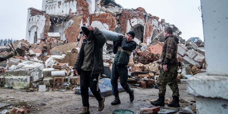 Volunteers carry remains of a Uragan rocket after a monastery was destroyed in a shelling in Dolyna, Ukraine