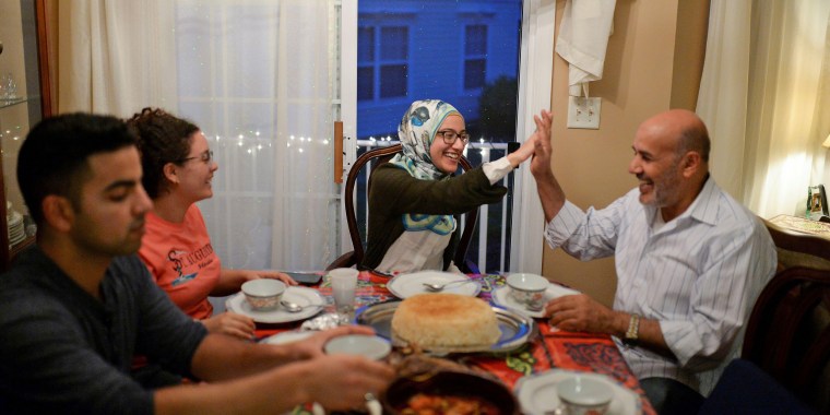 Hager Elhariry, center, high-fives family friend Ali Ghonaim as the Elhariry family breaks their fast during Ramadan in Manalapan, N.J., in 2017.