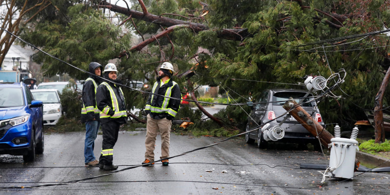 Emergency personnel look at damage to a utility pole after tree damage during a storm in Santa Rosa, Calif.