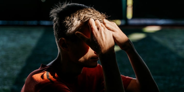 A man sits with his hands on his head.