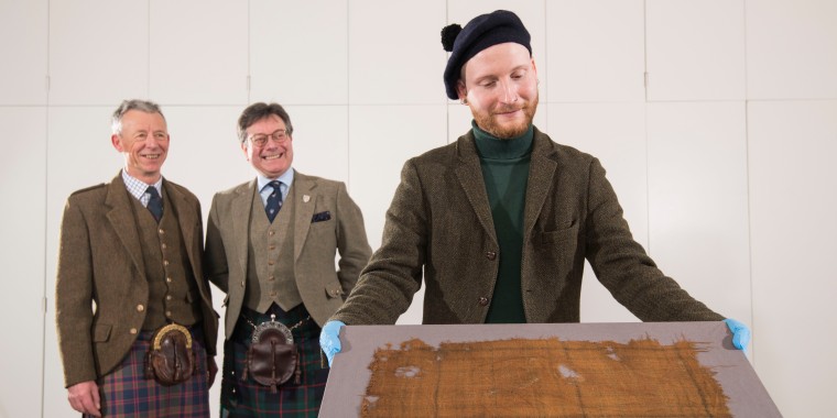 From left: Peter MacDonald, head of research and collections and John McLeish, chair of The Scottish Tartans Authority, bring the Glen Affric tartan to curator James Wylie to be exhibited at V&A Dundee's Tartan exhibition opening Saturday 1 April 2023.