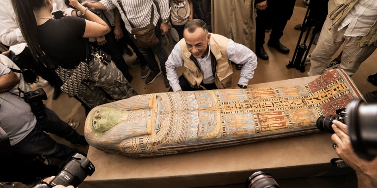 People surround Mostafa Waziri as displays a recently unearthed ancient wooden sarcophagus