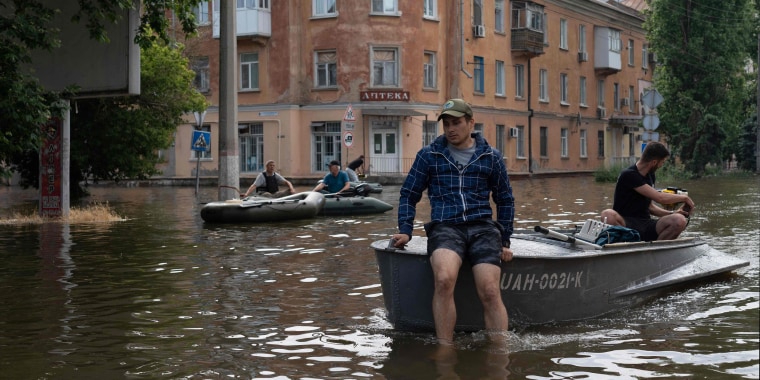 Volunteers carry local residents on boats during an evacuation from a flooded area in Kherson