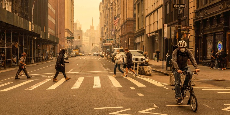 Pedestrians wear face masks as smoke from Canada wildfires blankets New York on June 7, 2023.