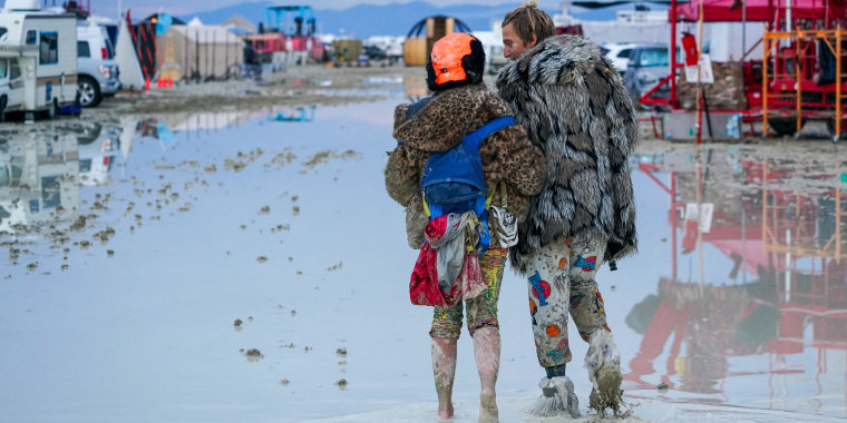 Burning Man attendees trudge through the mud in Black Rock City, Nev., on Sept. 2, 2023.