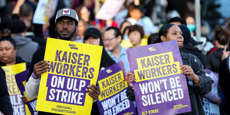 Striking Kaiser Permanente workers hold signs in front of the Kaiser Permanente San Francisco Medical Center.