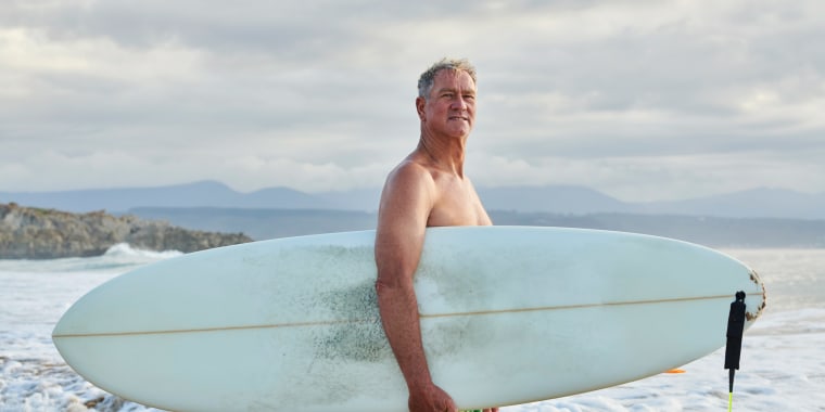 Older male surfer at beach.