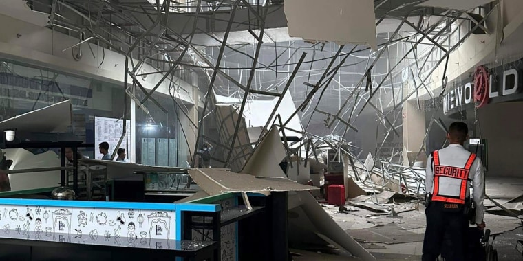 A security guard walks beside the damaged ceiling of a shopping mall in General Santos City, Philippines,