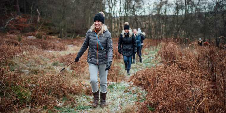 Four women are enjoying a walk through the woodland together in winter.