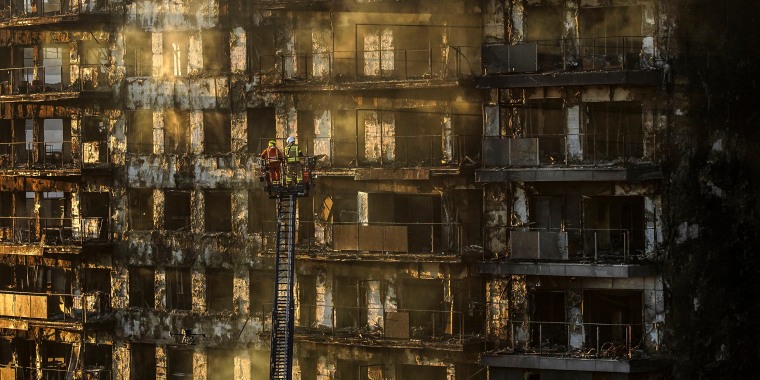 Image: Firefighters work at a burned block building in Valencia, Spain