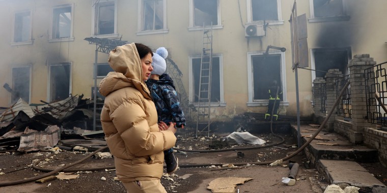 A woman and her child walks past the destroyed railway station.