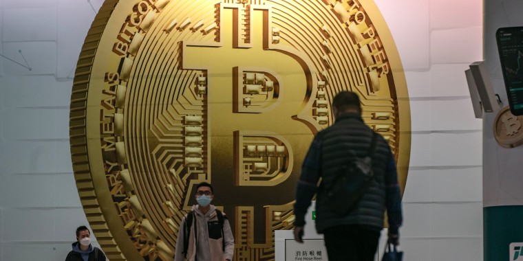 People walk past an ad for Bitcoin in Hong Kong