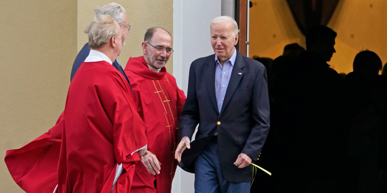 President Joe Biden greets clergy members while carrying a palm branch as he leaves St. Joseph on the Brandywine Catholic Church in Wilmington, Del., on March 23, 2024.