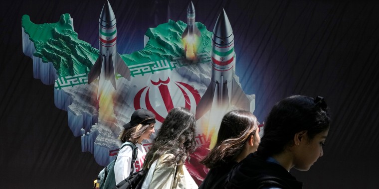 Iranians walk past a banner in Tehran, Iran, on April 19, 2024. 