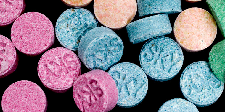 Colorful MDMA pills scattered around a black background