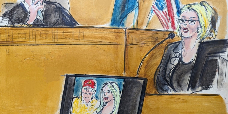 Courtroom sketch of Stormy Daniels testifies on the witness stand as Judge Juan Merchan looks on with a photo of Donald Trump and Daniels from their first meeting is displayed on a monitor