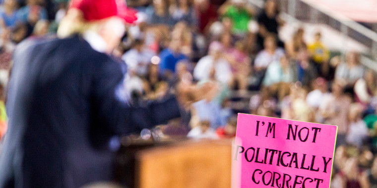 A supporter holds up a sign that reads" I'm not politically correct" in front of Donald Trump at a rally.