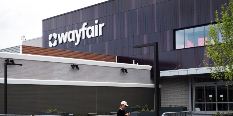 A person looks at their phone while walking in front of the new Wayfair store