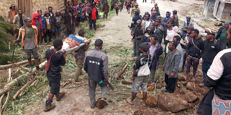 This handout photo by the International Organization for Migration (IOM) on May 25, 2024 shows locals carrying a person on a stretcher from the site of a landslide at Yambali Village in the region of Maip Mulitaka, in Papua New Guinea's Enga Province. Rescue teams began arriving at the site of a massive landslide in Papua New Guinea's remote highlands on May 25, helping villagers search for the scores of people feared dead under the towering mounds of rubble and mud.