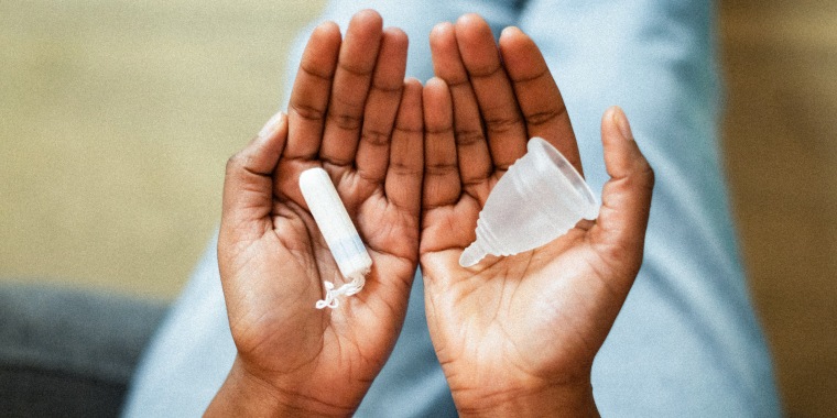Close up female hands holding cotton tampon and silicone menstrual cup