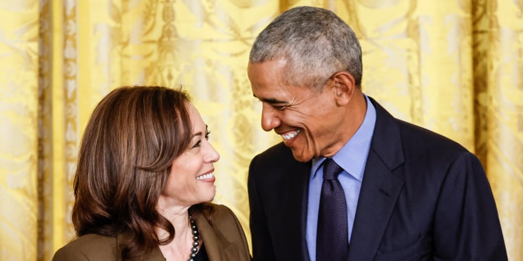 From left, Kamala Harris and Barack Obama smile at each other while standing side by side