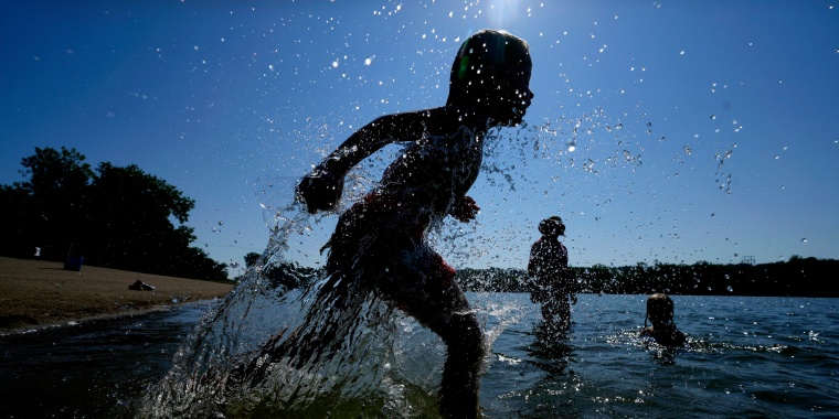 Judah Boyle, of Des Moines, Iowa, splashes water as he runs on the beach at Gray's Lake Park, Monday, Aug. 26, 2024, in Des Moines, Iowa. (AP Photo/Charlie Neibergall)