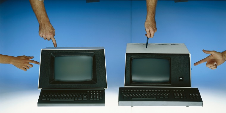 Human hands pointing at vintage computers