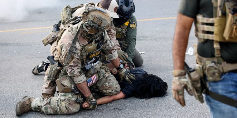 ICE agents detain a woman, pressing her against the ground outside