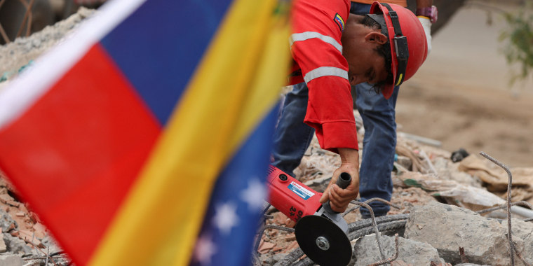 Un voluntario trabaja en los escombros de un edificio en La Guaira conforme venezolanos siguen buscando los restos de seres queridos para darles sepelio, el 18 de julio de 2026.