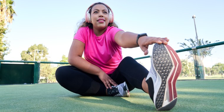 Latin woman with large build stretching after jogging