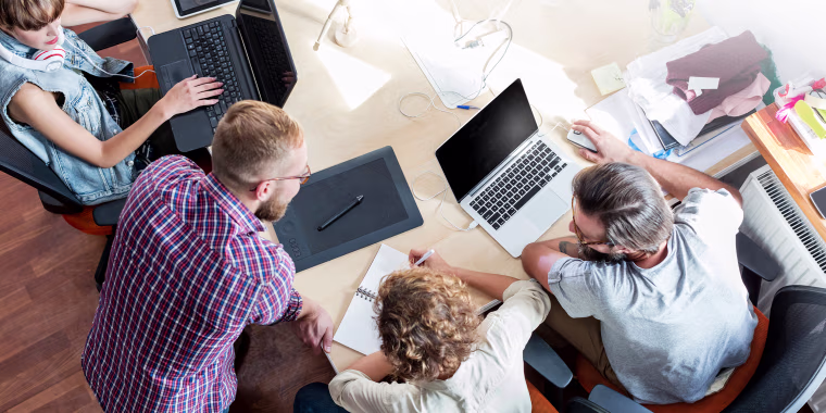 Image: People work at laptops during a meeting