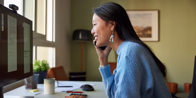 Businesswoman talking on smart phone at desk