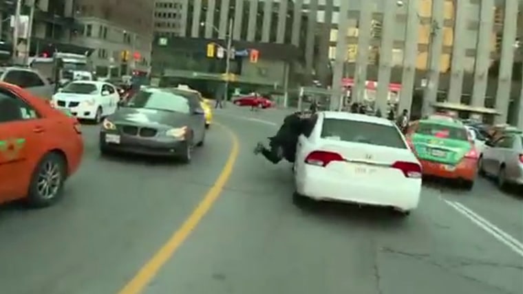 Video: Taxi driver protesting Uber grabs onto Uber car, is dragged