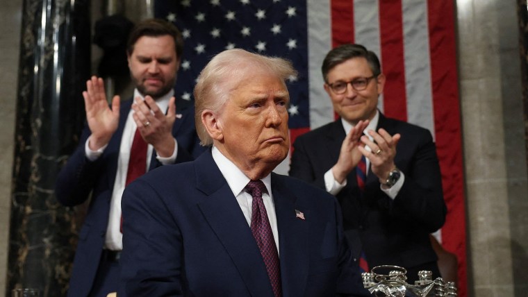 arafed image of a man in a suit and tie standing in front of a flag