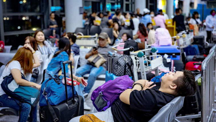A passenger asleep inside a crowded airport